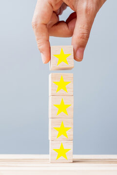 Hand holding wooden blocks with the star symbol. Customer reviews, feedback, rating, ranking and service concept.