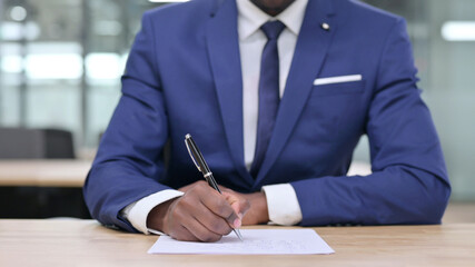 Close up of African Businessman Writing on Paper