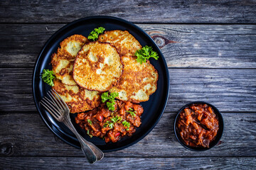 Potato pancakes with vegetable stew on wooden table
