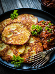 Potato pancakes with vegetable stew on wooden table
