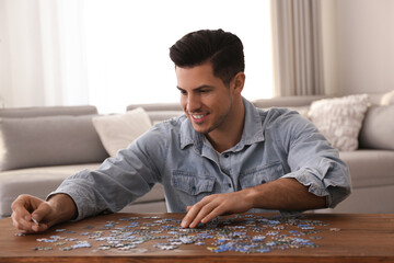 Man playing with puzzles at wooden table indoors