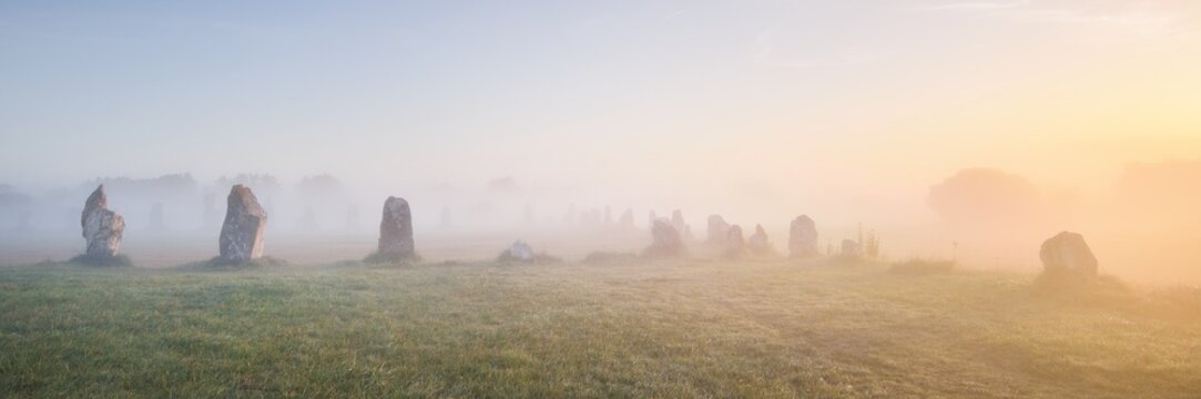 Menhir alignment view at Camaret sur mer in a morning fog at sunrise. Brittany, France. Golden light. Panoramic picturesque scenery. Travel destinations, national landmarks. sightseeing, history