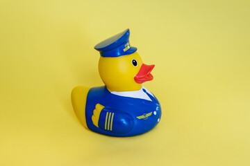 Rubber yellow duck in a blue pilot's suit on a yellow background.