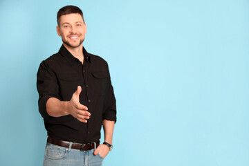 Fototapeta premium Businessman offering handshake against turquoise background, focus on hand. Space for text