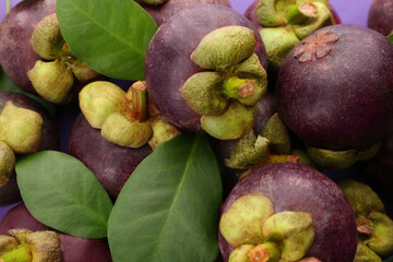 Delicious fresh mangosteen fruits with leaves as background, closeup