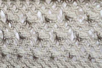 Weaving texture in macrame style from white natural cotton threads.