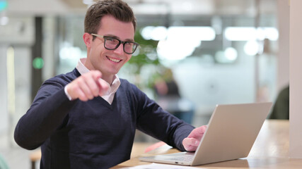 Young Businessman with Laptop Pointing at the Camera 