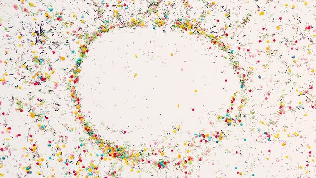 The hand makes a round frame for the inscription in the background of baking sprinkles. Time lapse video, 16x9 format. ProRes 422 HQ.