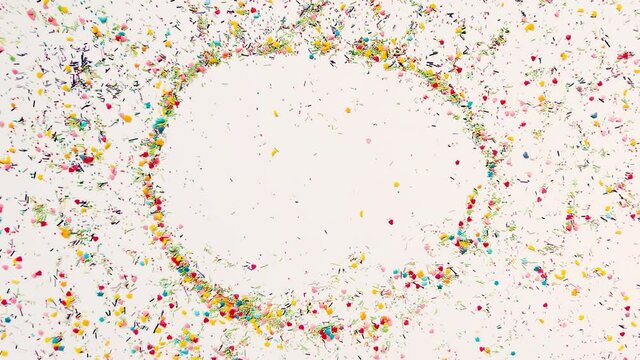 The hand makes a round frame for the inscription in the background of baking sprinkles. Time lapse video, 16x9 format. ProRes 422 HQ.