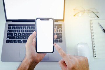 Young man working from home using smart phone and notebook computer and Holds a pen 