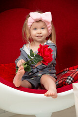 Beautiful little girl with a red rose. Baby barefoot with a flower.