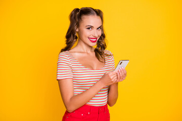 Portrait of attractive cheerful girl using gadget browsing multimedia comment isolated over bright yellow color background