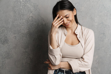 Brunette hispanic woman covering her face and smiling at camera