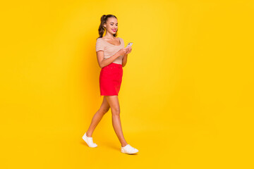 Fototapeta na wymiar Full length body size view of attractive cheerful thin focused girl using device going isolated over bright yellow color background