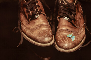 A pair of brown vintage leather shoes with a butterfly brooch on a dark background. Beautiful...