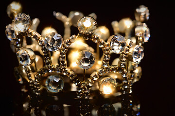 Gold crown with shiny stones on a black background.