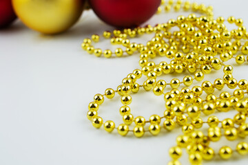 Christmas toys on a white background close-up, red, gold, yellow glass balls, gold beads, Christmas decorations on the Christmas tree