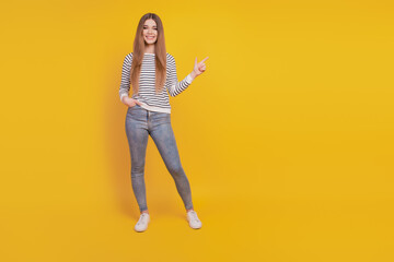 Portrait of lovely adorable woman indicate way finger direct empty space on yellow wall