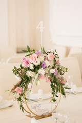 Centerpiece made of green leaves and fresh flowers stands on the dinner table. Wedding day. Fresh flowers decorations.
