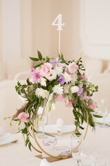Centerpiece made of green leaves and fresh flowers stands on the dinner table. Wedding day. Fresh flowers decorations.