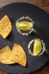 Golden tequila with lime slices and nacho chips