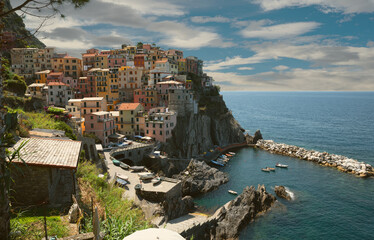 Fototapeta na wymiar Manarola, Liguria, Italy. June 2020. Amazing view of the seaside village. The colored houses leaning on the rock near the sea are particularly fascinating and characteristic. Beautiful summer day.