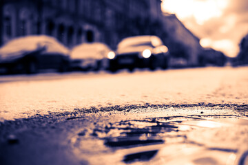 Bright winter sun in a big city, the headlights of the approaching car. Close up view of a hatch at the level of the asphalt