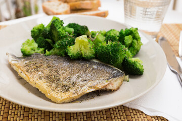 dish of fried dorado fish fillet with boiled broccoli