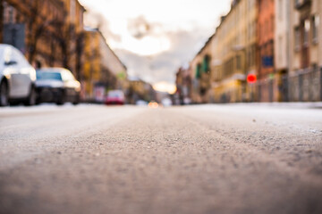 Bright winter sun in a big city, the empty road with parked cars. Close up view from the asphalt level