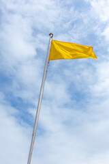 Yellow flag on a background of clouds, on a beach in Asturias, warning of the danger of the beach's waters.