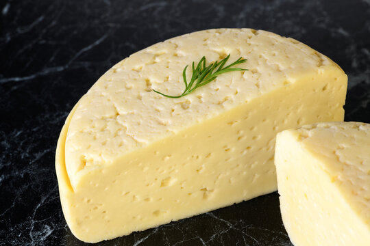 Piece of cheese with dill on black background. Homemade products