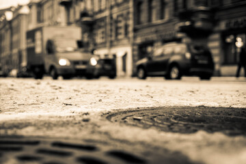 Snowy winter in the big city, the cars traveling on a busy street. Close up view of a hatches at the level of the asphalt