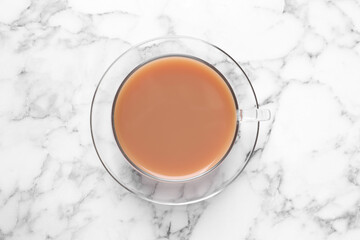 Delicious milk tea in glass cup on white marble table, top view