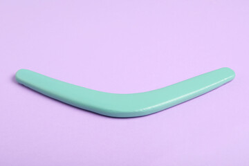 Turquoise boomerang on lilac background. Outdoor activity