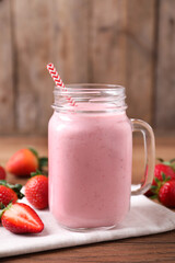 Delicious strawberry drink in mason jar on wooden table
