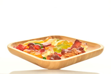 Several sweet jelly candies with a bamboo plate, close-up, isolated on white.