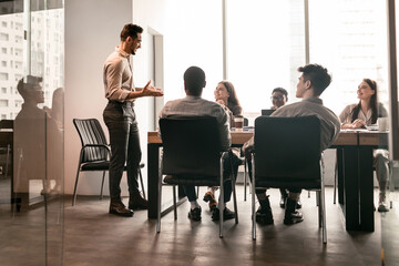 Colleagues having meeting in boardroom, businessman giving speech