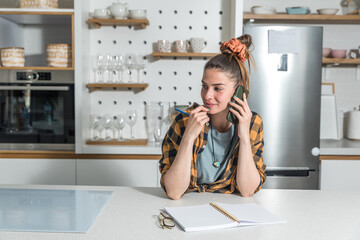 Young beautiful woman from a catering company stands in the kitchen and calls the client in charge of planning the wedding about the amount and type of food needed for the celebration