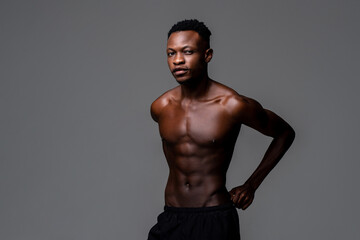 Studio shot portrait of shirtless fit young handsome African man in isolated gray studio background