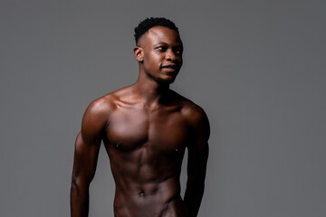 Fototapeta premium Waist up studio portrait of shirtless young lean fit African man in isolated light gray background