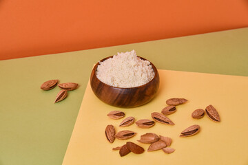 almond flour in a wooden bowl on a colorful background with nuts
