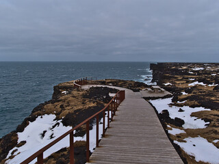 Wooden footpath with railing above the Svörtuloft cliffs on the northwestern coast of...