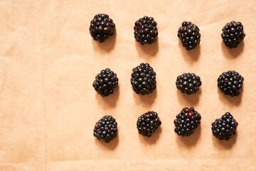 Twelve blackberries on a beige craft paper background. Berries laid out in the form of a rectangle. Horizontal card with copy space. Healthy, delicious, natural vegetarian background.