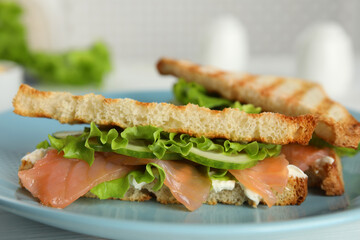 Tasty sandwiches with salmon on blue plate, closeup