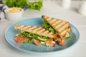 Blue plate with tasty sandwiches on white table