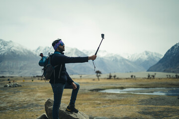 Young and handsome male travel blogger recording a video for vlog with his Go Pro action camera,...