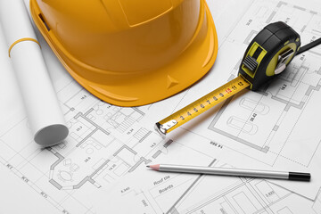 Pencil, measuring tape and hardhat on blueprints