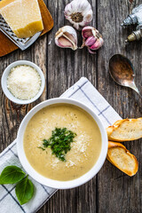 Cream garlic and parmesan soup on wooden table
