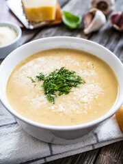 Cream garlic and parmesan soup on wooden table
