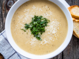 Cream garlic and parmesan soup on wooden table
